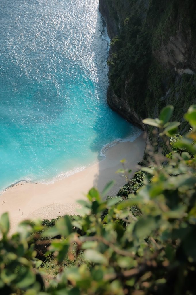 Turquoise beach below green cliffs on the coast of Bali